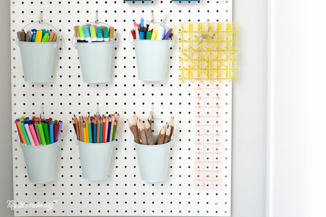 Close up of a pegboard hanging on a wall, filled with markers and more