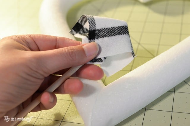 foam heart and black and white fabric square folded over in woman's finger