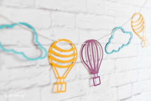 side view of colorful hot air balloon and cloud SVG files cut on paper and strung against background