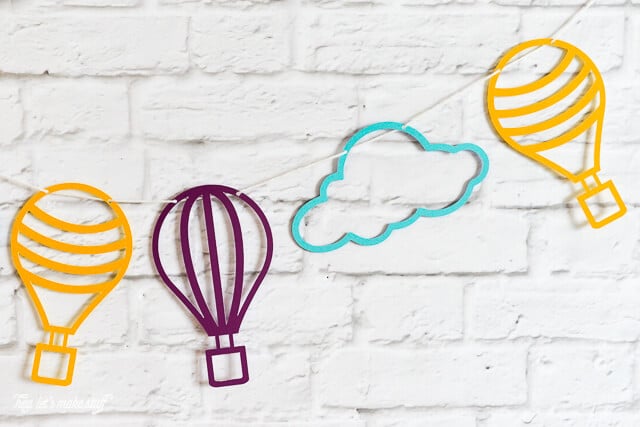 close up of colorful hot air balloon and cloud SVG files cut on paper and strung against background