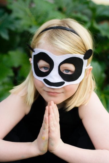 A close up of a young girl wearing a Kung Fu Panda mask