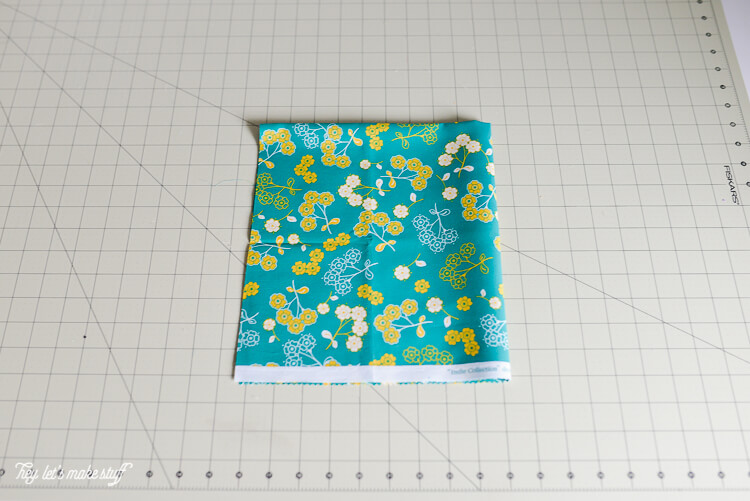 piece of fat quarter fabric folded into a quarter on a sewing mat