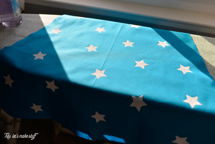A piece of blue fabric with white stars on an ironing board