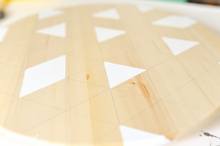 A round piece of wood with white painted triangles and diamonds