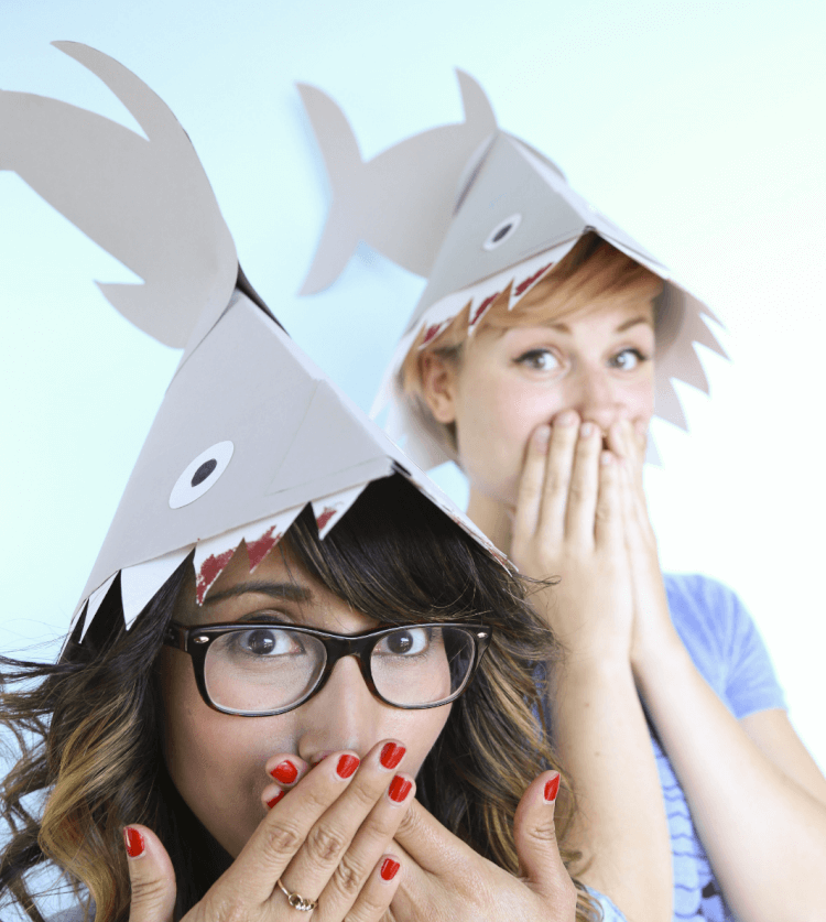 Two women wearing shark hats make out of paper