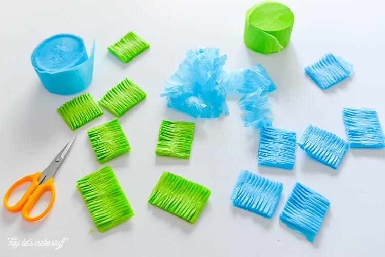 Rolls of blue and green crepe paper and strips of paper cut with fringe
