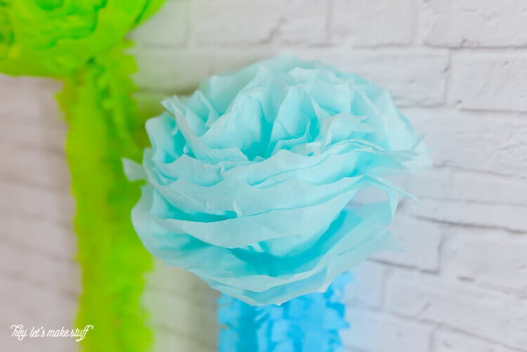 A close up of a flower made with green and blue tissue paper