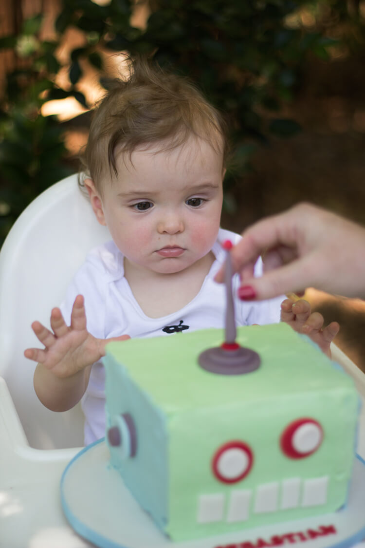 A little boy sitting at a table with a birthday cake