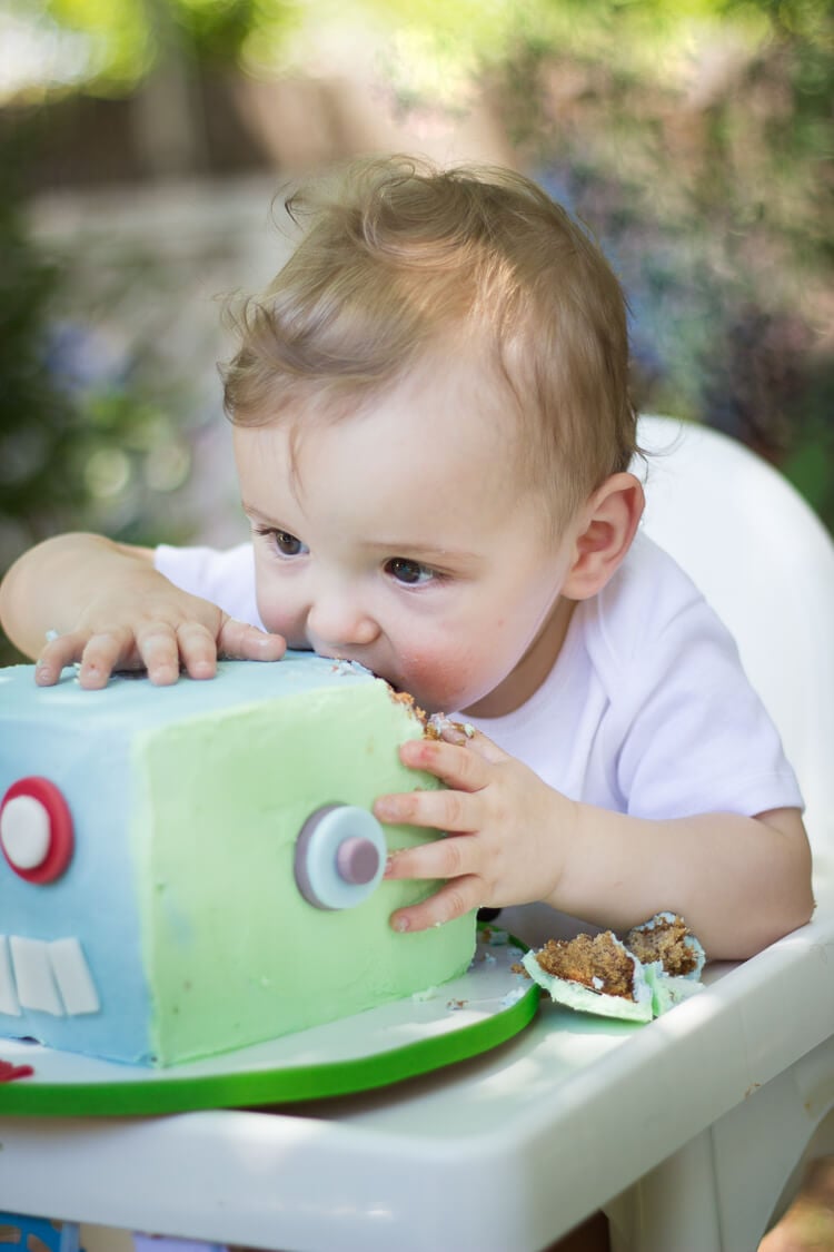 A baby sitting in a high chair eating a cake