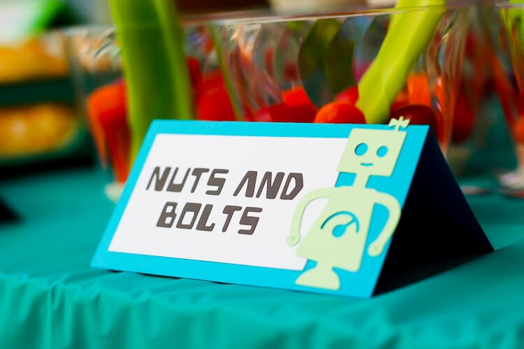 A sign up against a glass that has an image of a robot on it and says, \"Nuts and Bolts\"