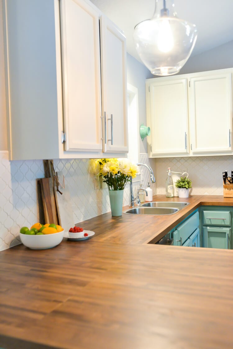 A kitchen with white and teal cabinets and stainless-steel appliances