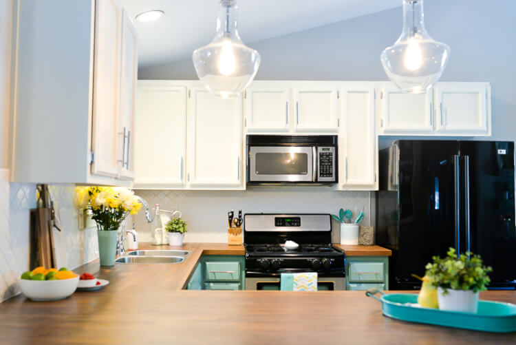 A kitchen with white and teal cabinets and stainless-steel appliances