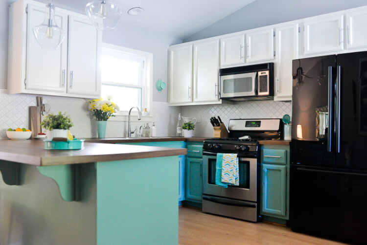 A kitchen with white and teal cabinets and stainless-steel appliances
