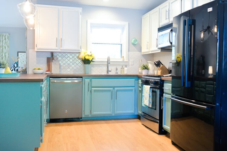 A kitchen with white and teal cabinets and stainless-steel appliances