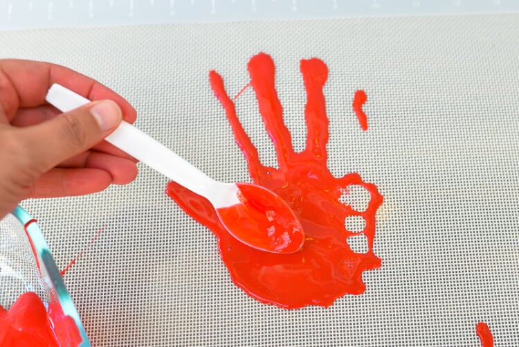 A person using a spoon to create a bloody handprint