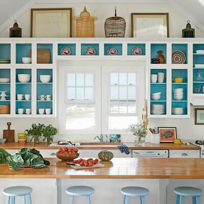 A kitchen with white cabinets that are painted a teal color on the inside