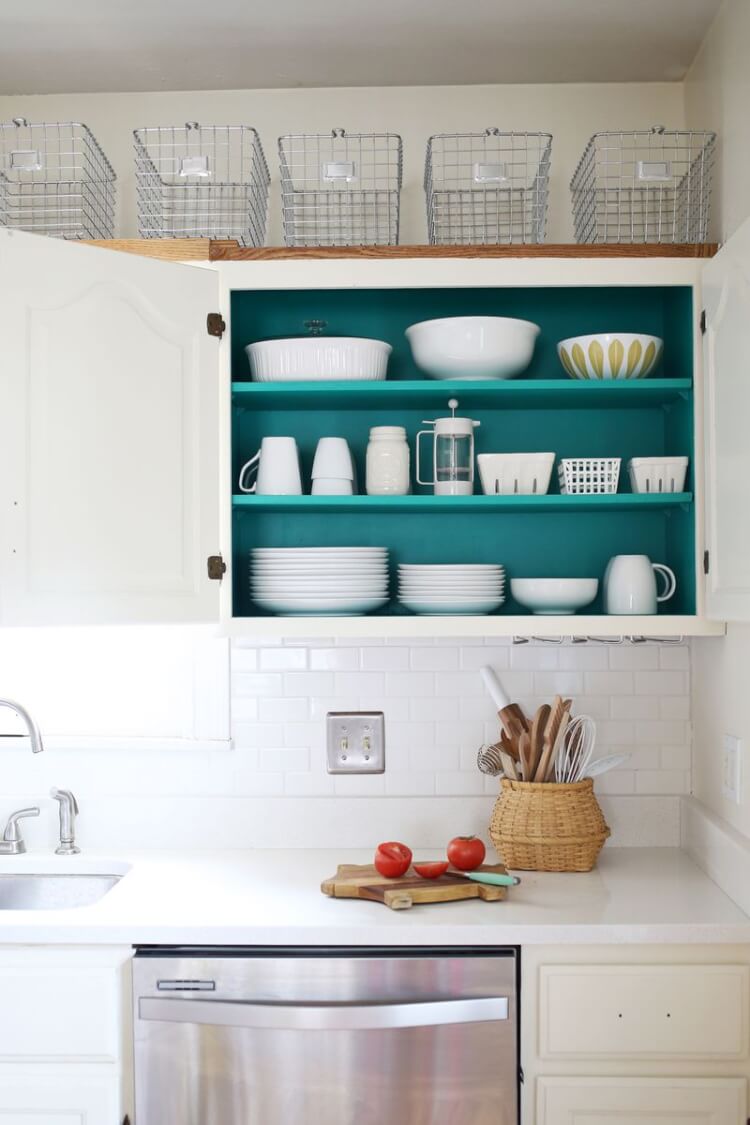 A kitchen with white cabinets that are painted a teal color on the inside