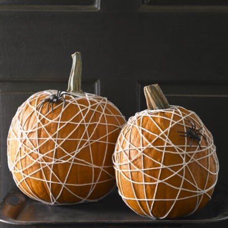 Two pumpkins wrapped in string to look like spider web