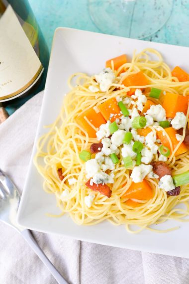 Close up of a bowl of butternut squash pasta with blue cheese and bacon sitting on table