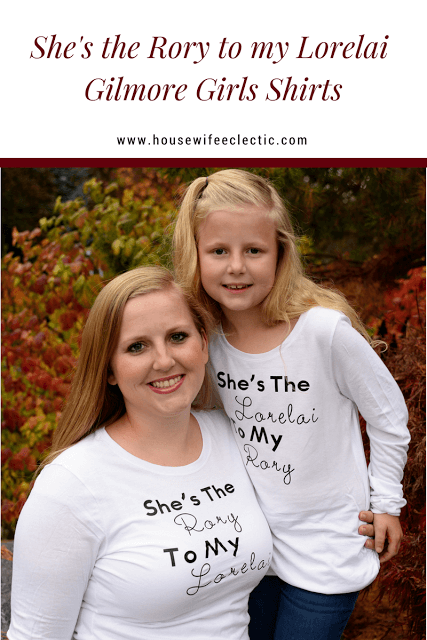 A woman and a little girl wearing white long-sleeved t-shirts that say, \"She\'s the Rory to my Lorelai\" on the woman\'s shirt and \"She\'s the Lorilai to my Rory\" on the little girl\'s shirt