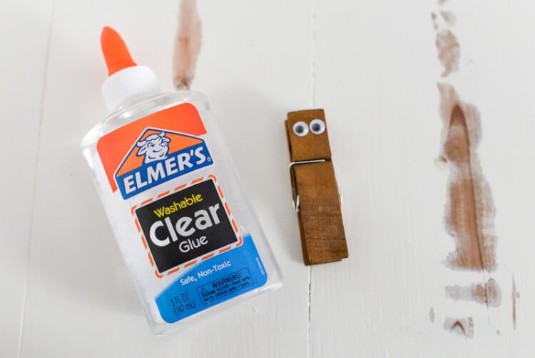 Elmer\'s glue next to a clothespin decorated with googly eyes