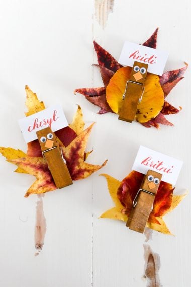 Place card Holders made to look like turkeys using leaves from a tree and clothespins and personalized with names