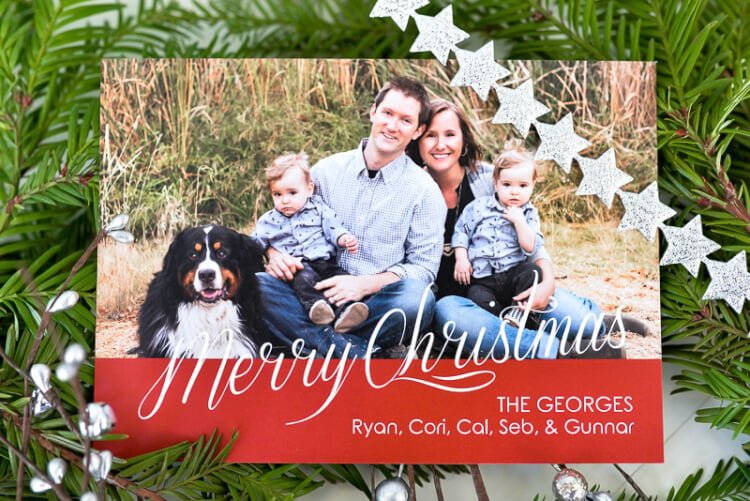 A close up of a Christmas card next to some holiday greenery on a table