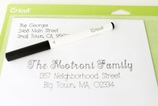 A Cricut pen and an addressed envelope sitting on top of a green Cricut mat