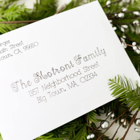 An addressed envelope sitting on top of some holiday greenery on a table