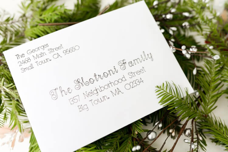 An addressed envelope sitting on top of some holiday greenery on a table