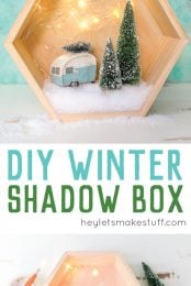 A wooden hexagon shaped shadow box that contains a retro camper with a small bottle brush tree on top of it and two other bottle brush trees standing next to the camper surrounded by fake snow and twinkle lights with advertising from HEYLETSMAKESTUFF.COM for DIY Winter Shadow Box