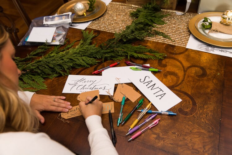 A person sitting at a table with a place settings, paper and pens