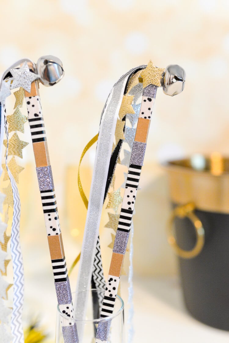 Close up of two party streamers with bells on them stuck inside a champagne flute
