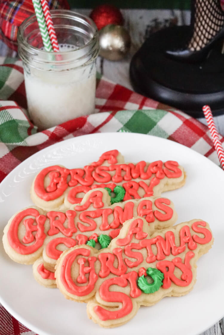 On a table sits a glass of milk and a plate of large cookies that are decorated with the words, \"A Christmas Story\" on them