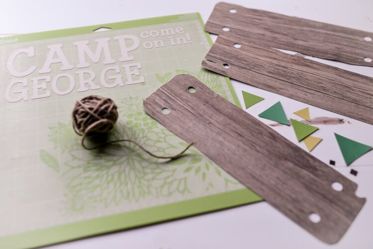 Pieces of wood, some twine and a design cutout on a green Cricut mat