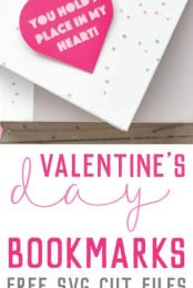 A book lying on a table with two Valentine bookmarks laying on top of it that say, "You Hold a Place in my Heart!" with advertising for free SVG cut files for Valentine's Day bookmarks from HEYLETSMAKESTUFF.COM