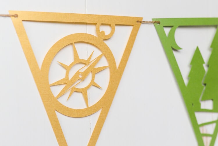 A close up of camping pennants, one of trees and one of a sundial