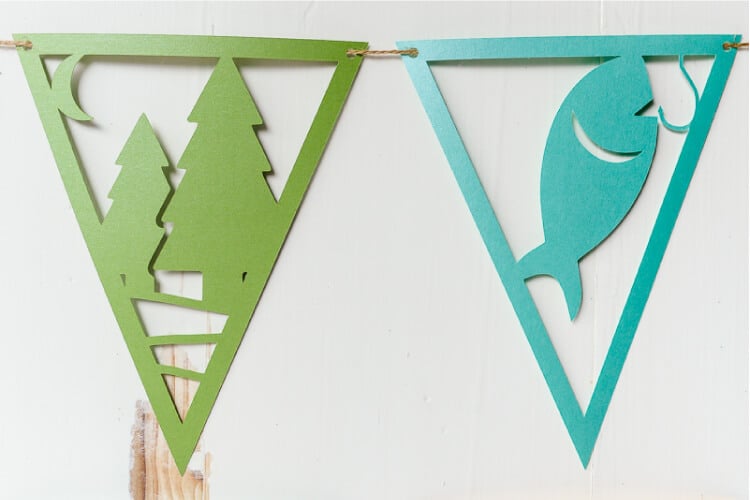 A close up of camping pennants, one of tress and one of a fish