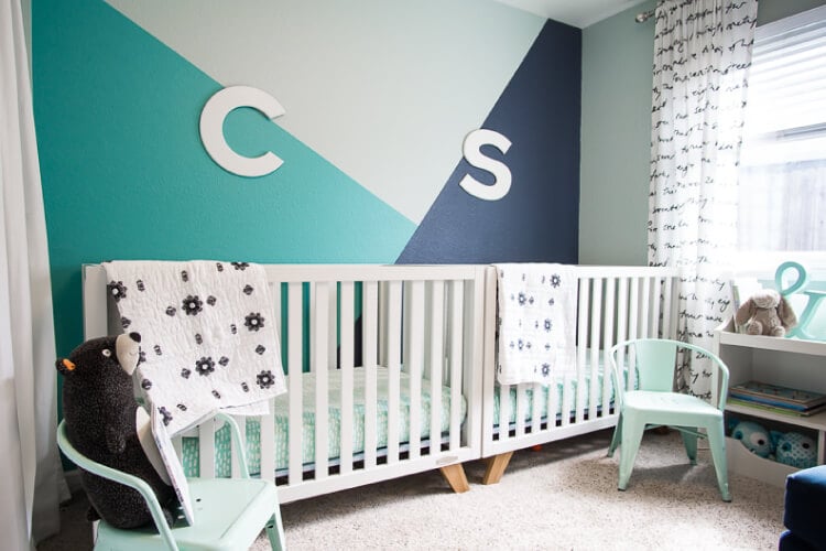 A nursery with two cribs, two mint green chairs and walls painted in dark blue, aqua blue and mint green.  Walls are decorated with the initial\'s \"C\" and \"S\"
