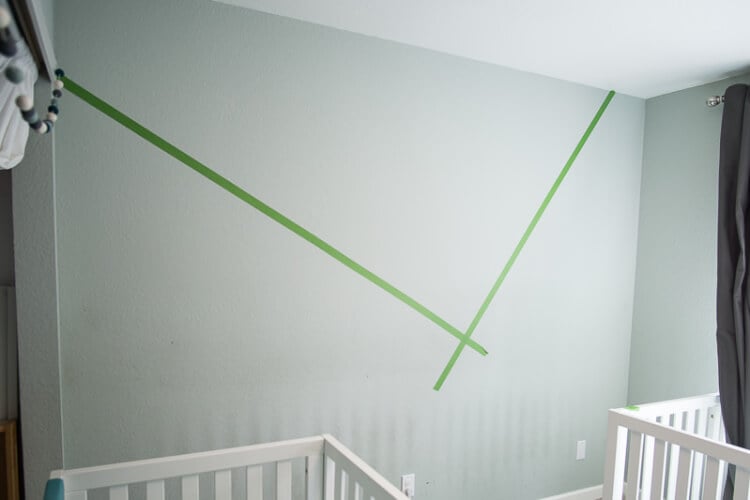 A baby crib and a wall marked off with green painter\'s tape