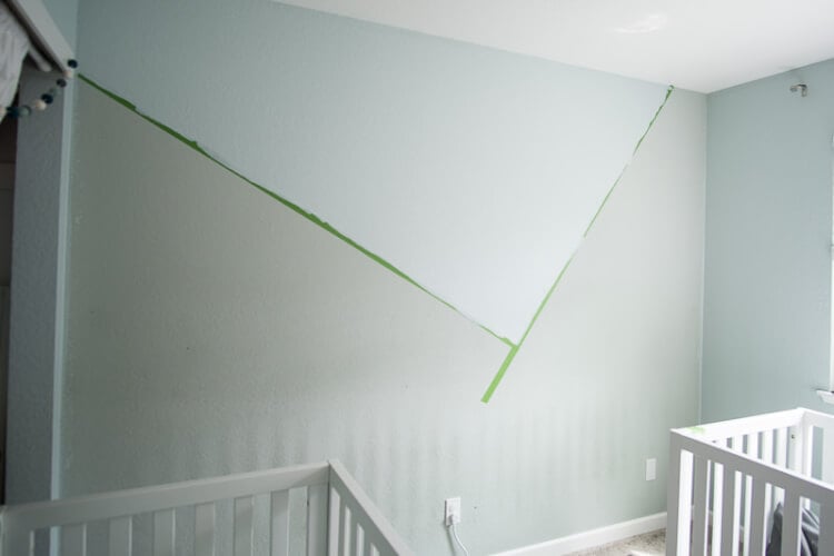 Two baby cribs and a wall marked off with green painter\'s tape