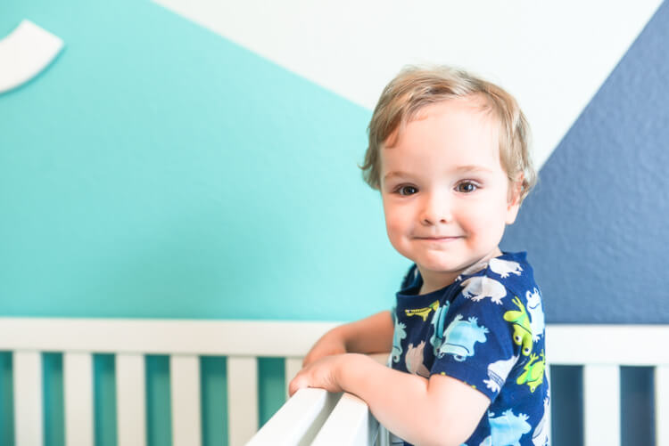 A small child standing up in a crib