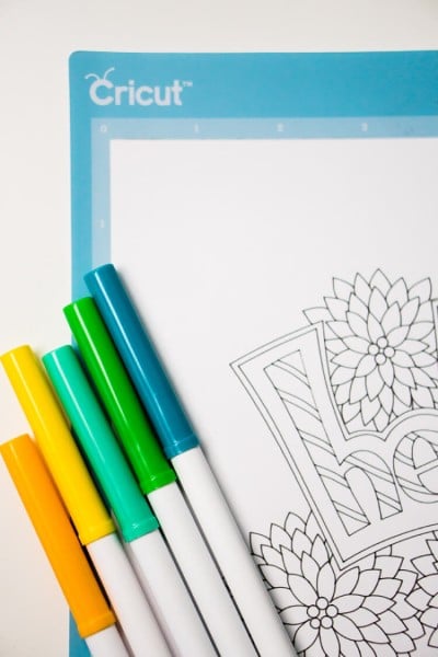 Five markers laying on top of a coloring page