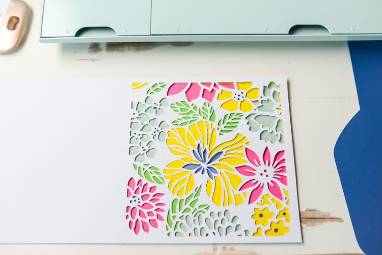 Picture of a floral design with a dimensional look next to a Cricut Explore Air 2 machine