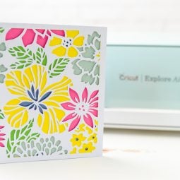 Picture of a floral design with a dimensional look next to a Cricut Explore Air 2 machine