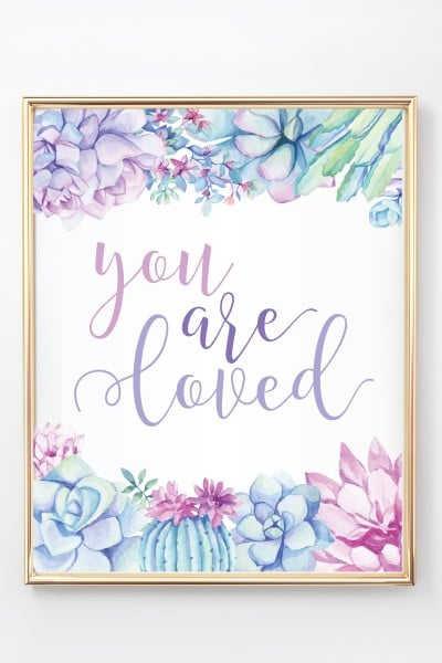 A gold framed picture of purple succulents and the saying, "You Are Loved"