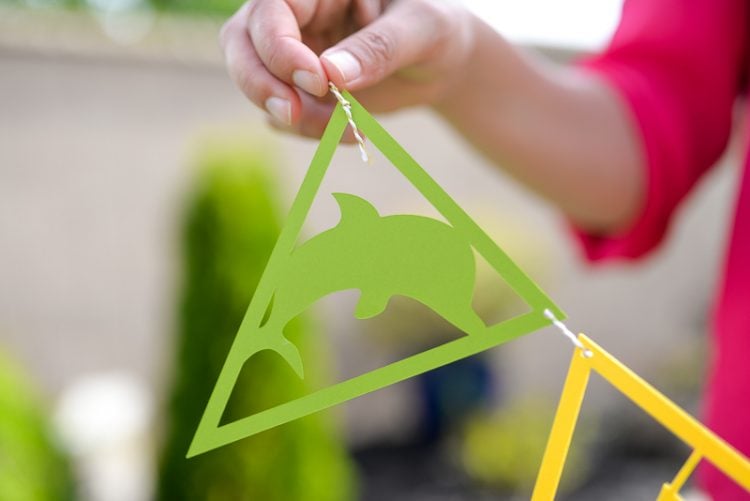 Close up of a lady holding a string of tropical themed party pennants