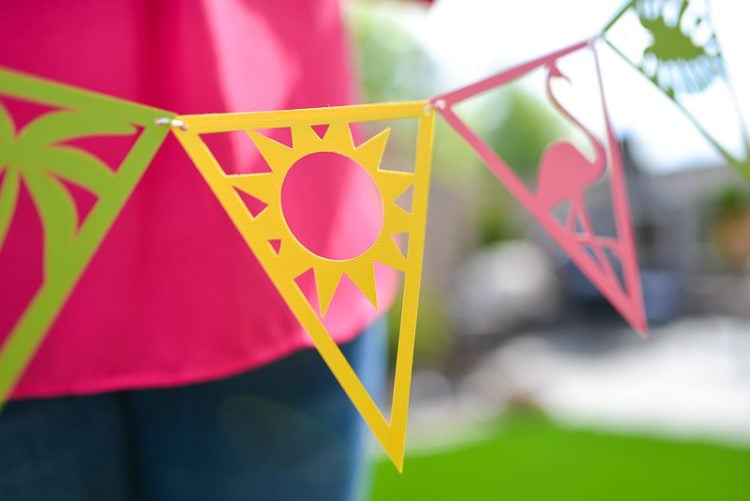 Close up of a lady holding a string of tropical themed party pennants