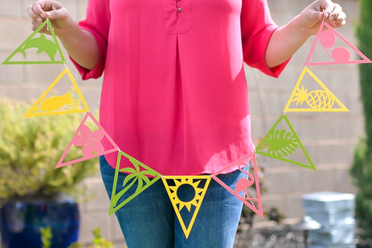 A lady holding a string of tropical themed party pennants