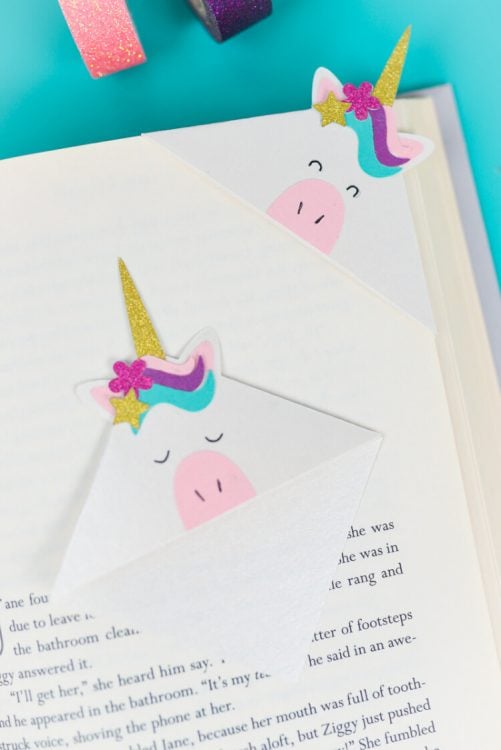 Washi tape next to an open book with two unicorn bookmarks on top of it